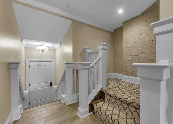 A staircase with a white railing and a brown carpeted stairway at The Knights @ 506 Delaware Apartments, Buffalo, New York