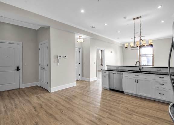 a kitchen and living room with white cabinets and a wooden floor at The Knights @ 506 Delaware Apartments, Buffalo