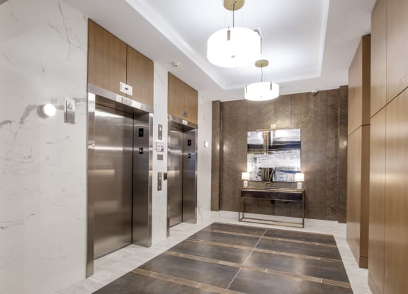 a lobby with stainless steel refrigerators and elevators and marble floors at Nineteen North, New York, 14202