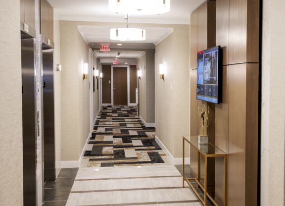 a long corridor with elevators and a carpeted hallway with a tv and elev at Nineteen North, New York