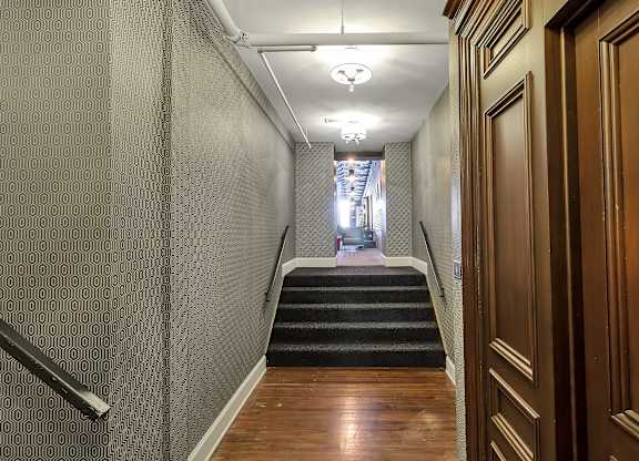 a long hallway with stairs and wood flooring and a hallway with doors and stairs at The Knights @ 506 Delaware Apartments, Buffalo, 14202