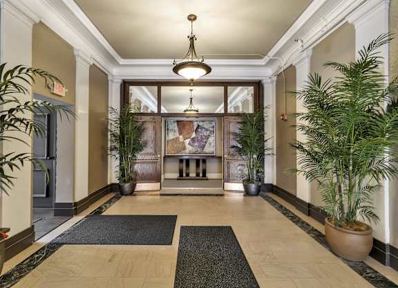 a lobby with potted plants and a large glass door at The Knights @ 506 Delaware Apartments, Buffalo, New York