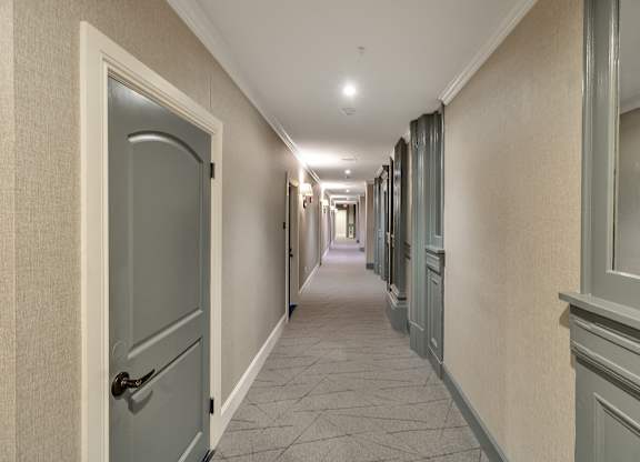 a hallway with blue doors and white walls and a tiled floor at The Knights @ 506 Delaware Apartments, Buffalo, 14202