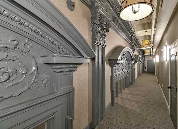 a long hallway with a long row of columns and a ceiling light at The Knights @ 506 Delaware Apartments, Buffalo, NY