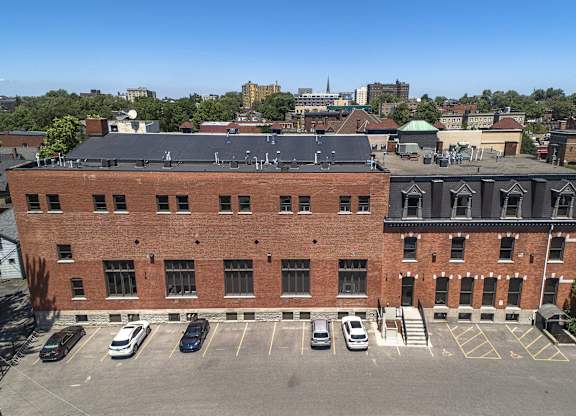 an aerial view of a brick building with cars parked in front of it at The Knights @ 506 Delaware Apartments, Buffalo, 14202
