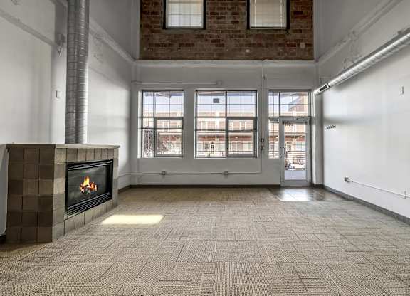 Loft living room with fireplace and large windows at The Lofts at Elk Terminal Apartments, New York, 14204