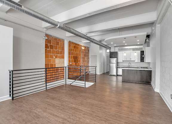 Loft living area with exposed brick and modern kitchen at The Lofts at Elk Terminal Apartments, Buffalo, NY