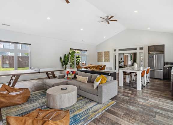 A modern living room with a grey couch and a round ottoman. at Highland Village, Ross Township, Pittsburgh, PA 15229