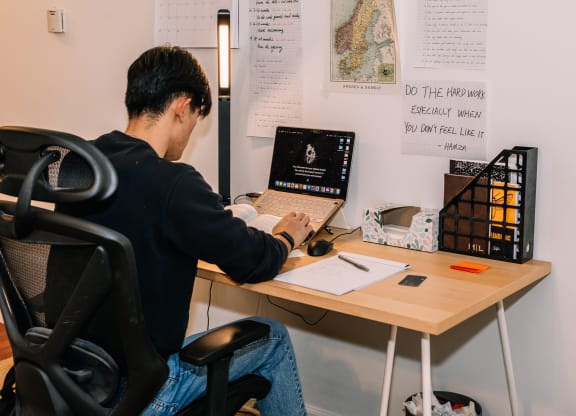 a man sitting at a desk with a laptop at University Commons Apartments, Oakland, Pittsburgh