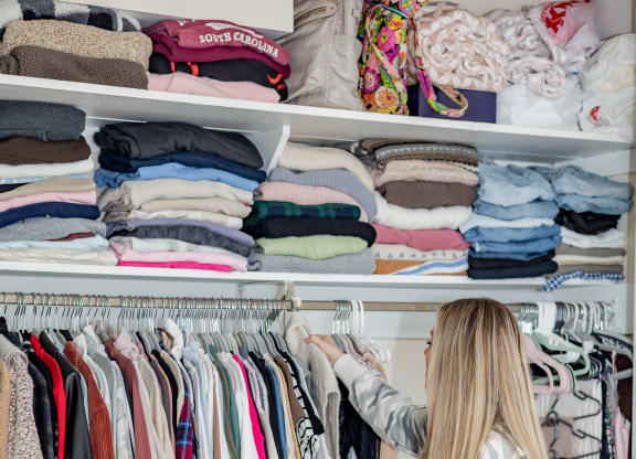 a woman standing in front of a closet full of clothes at University Commons Apartments, Oakland, Pittsburgh