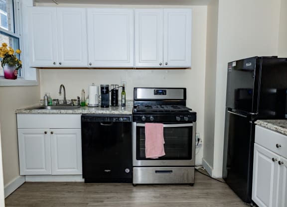 a kitchen with white cabinets and black appliances at University Commons Apartments, Oakland, Pittsburgh