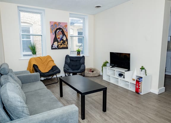 a living room with a couch coffee table and chairs and a tv on a stand at University Commons Apartments, Oakland, Pittsburgh