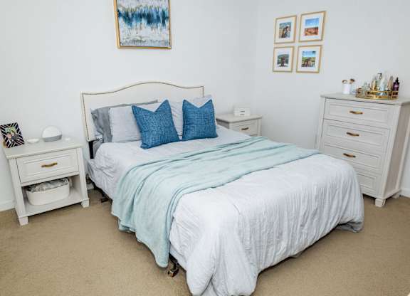 A bedroom with a bed, nightstand, and a painting on the wall. at Highland Village, Ross Township, Pittsburgh, PA 15229