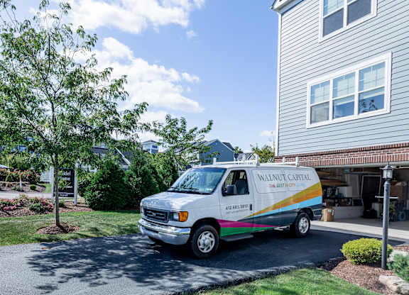 A white van with a rainbow stripe is parked in front of a house. at Highland Village, Ross Township, Pittsburgh, PA 15229