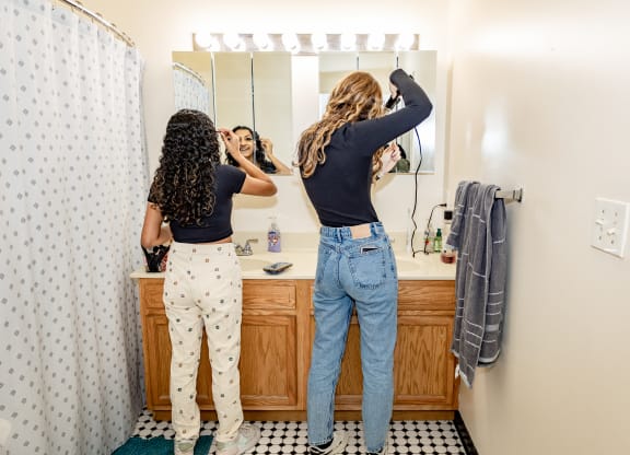 two women doing their hair in a bathroom at University Commons Apartments, Oakland, Pittsburgh
