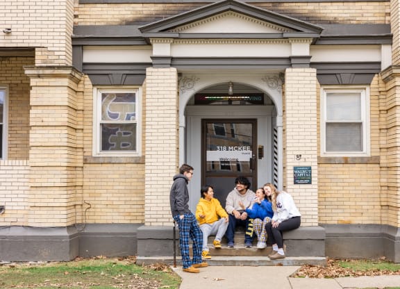 a group of people sitting on the steps of a building at University Commons Apartments, Oakland, Pittsburgh
