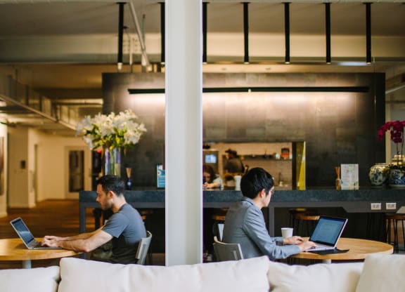 two men sitting at tables working on their laptops in a large open space at Bakery Living in Pittsburgh, PA 15206