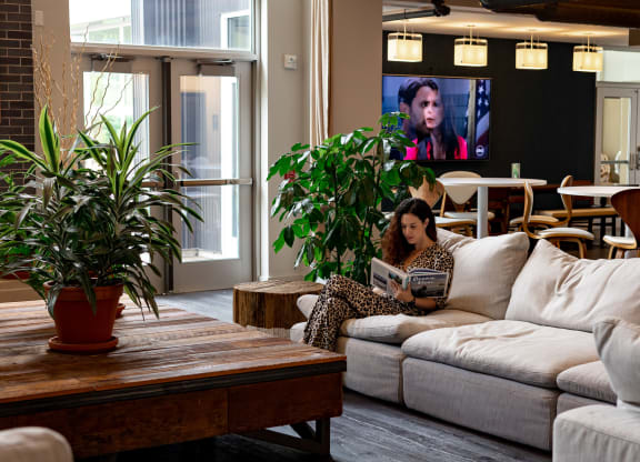 a woman sitting on a couch in a living room with a tv in the background at Bakery Living in Pittsburgh, PA 15206