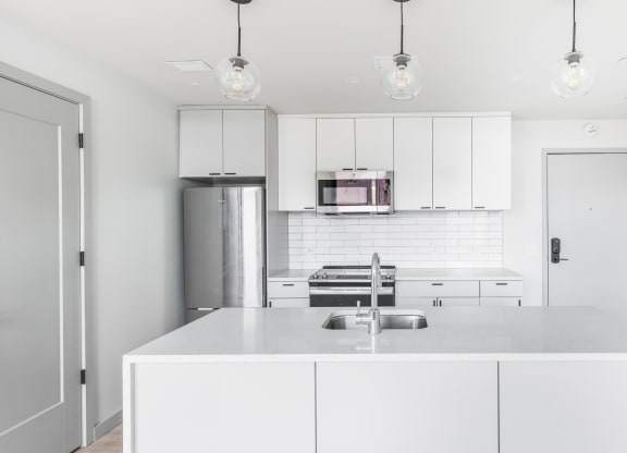 a white kitchen with white cabinets and stainless steel appliances at The Commonwealth Building, Pittsburgh, Pennsylvania