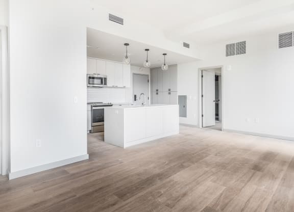an empty living room and kitchen with white walls and wood floors at The Commonwealth Building, Pittsburgh, Pennsylvania