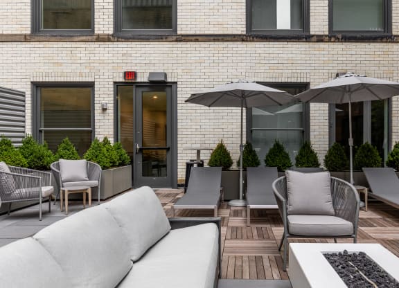 a patio with couches chairs and umbrellas in front of a brick building at The Commonwealth Building, Pittsburgh, 15222