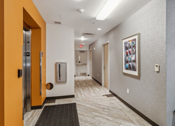 A hallway with a bench and a framed picture on the wall.