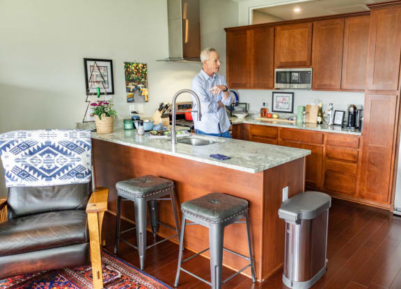 a man stands at a kitchen counter with a sink and three stools at The Washington at Chatham, Pittsburgh, PA 15219