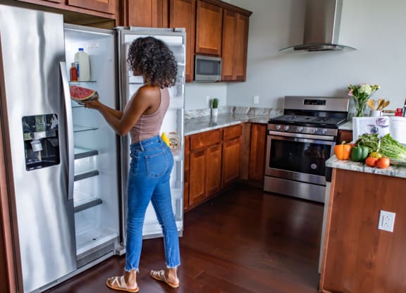 a woman standing in a kitchen looking in a refrigerator at The Washington at Chatham, Pittsburgh