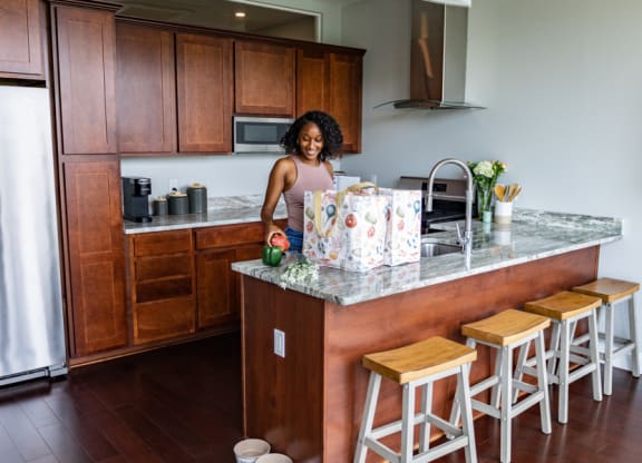 a woman standing at a kitchen counter with a christmas present at The Washington at Chatham, Pittsburgh Pennsylvania