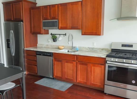 a kitchen with wood cabinets and stainless steel appliances at The Washington at Chatham, Pennsylvania, 15219