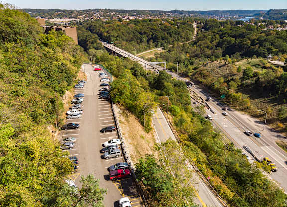 A parking lot with cars is situated on a hillside at Walnut Towers at Frick Park, Pittsburgh, PA