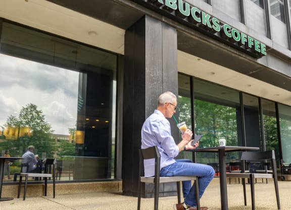 a man sitting in a chair outside a coffee shop at The Washington at Chatham, Pennsylvania, 15219