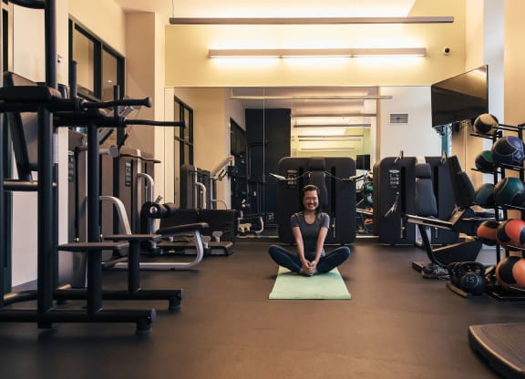 a woman sitting on a yoga mat in a gym at Walnut on Highland, Pittsburgh, PA