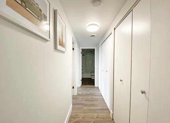 A long hallway with white walls and wood flooring at Walnut Towers at Frick Park, Pittsburgh, Pennsylvania
