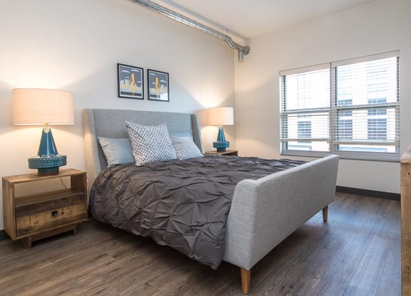 a bedroom with a bed and two windows Hot Metal Flats apartments, Southside Pittsburgh, PA