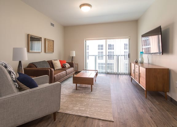 a spacious living room with a sliding glass door leading to a balcony Hot Metal Flats apartments, Southside Pittsburgh, PA