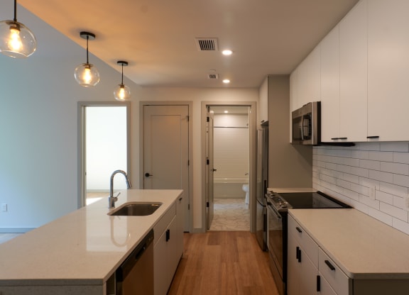 a kitchen with white counters and white cabinets and a door to a hallway at The Commonwealth Building, Pittsburgh, 15222