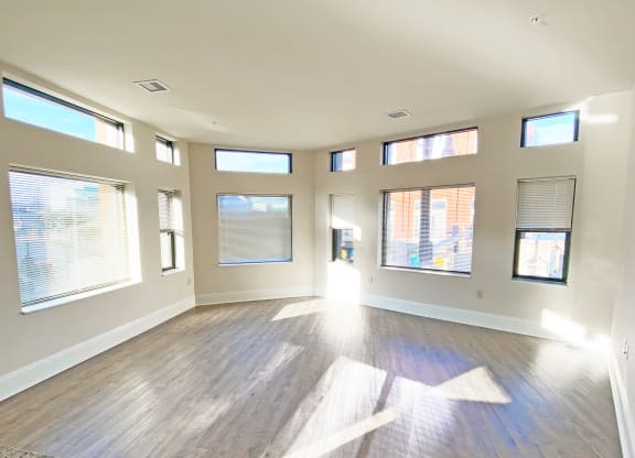 an empty living room with windows and hardwood floors at Walnut on Highland, Pittsburgh, PA