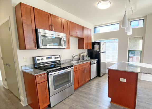 a kitchen with wooden cabinets and stainless steel appliances at Walnut on Highland, Pittsburgh, PA
