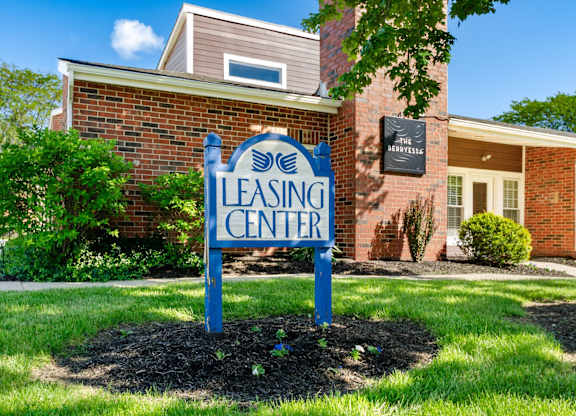 A blue sign that says Leasing Center in front of a brick building.