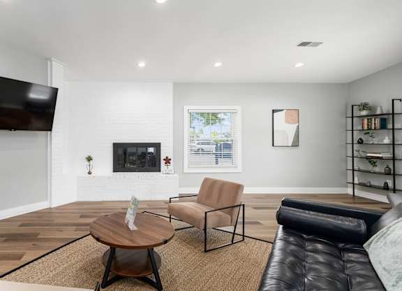 A living room with a fireplace, a chair, a coffee table, and a TV.