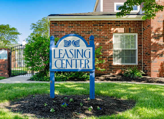 A blue sign that says Leasing Center in front of a brick building.
