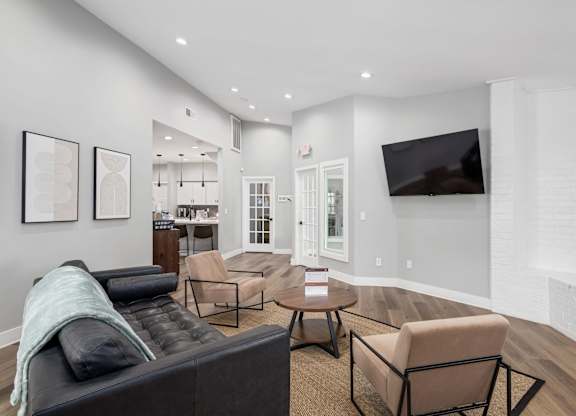 A living room with a black couch and a television on the wall.
