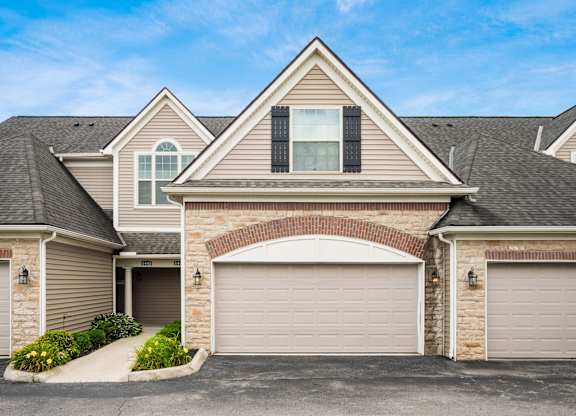 A house with a grey garage door and a brick archway above it. at River View at Bexley Apartments, River View at Bexley, OH