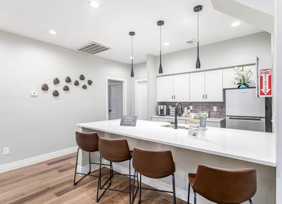 A kitchen with white countertops and brown chairs.