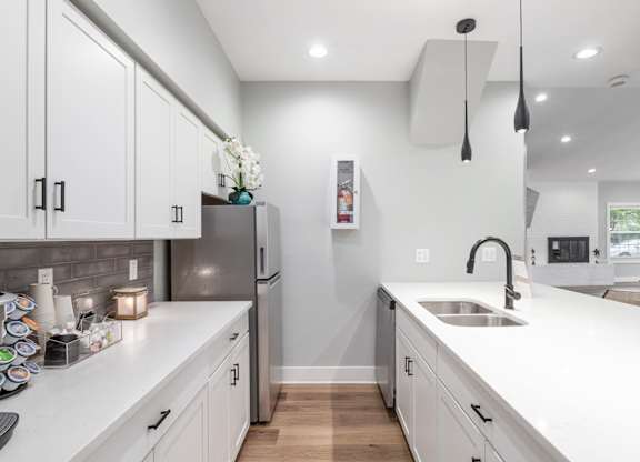 A kitchen with white cabinets and a grey backsplash.