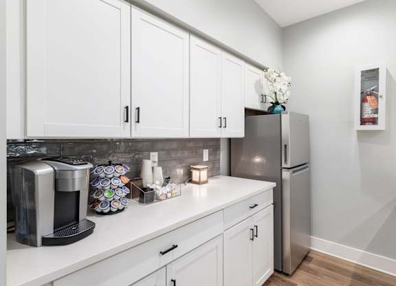 A kitchen with white cabinets and a stainless steel refrigerator.