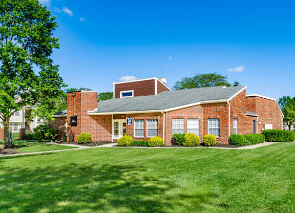 A red brick building with a green lawn in front.