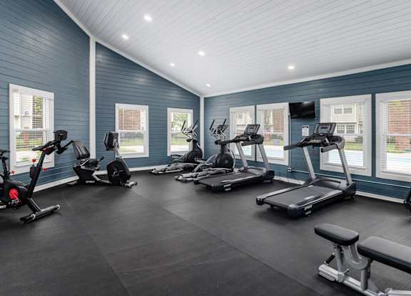 A spacious gym with treadmills, exercise bikes, and a bench.