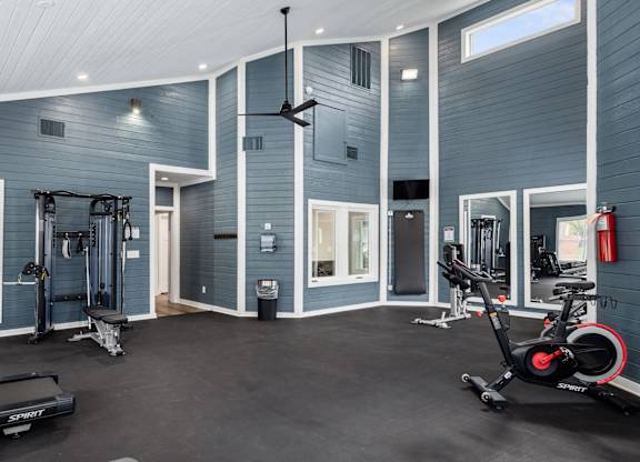 A gym with a variety of equipment including a treadmill, a stationary bike, and a weight bench.